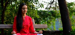 A young woman meditating on a bench in the woods